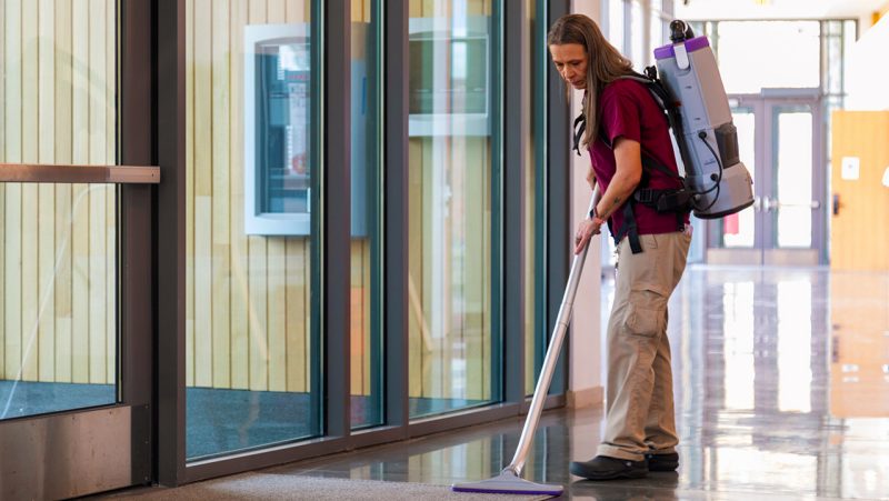 A housekeeping employee vacuuming in a residential hall 